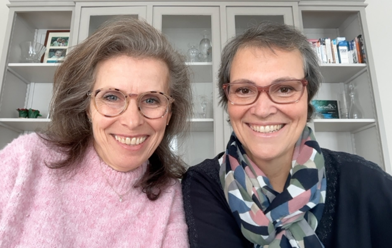 Portrait de face d'Isabelle et Carole, co-fondatrices de Ticket To Your Job, souriantes devant une bibliothèque claire.